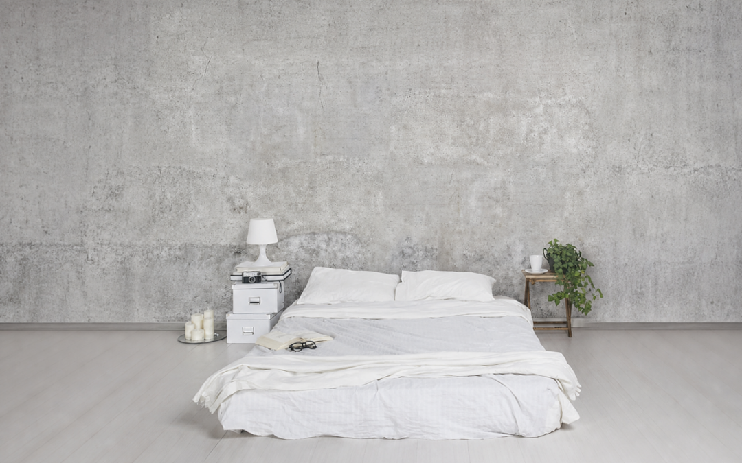Schlafzimmer mit grauer Vliestapete in Shabby-Betonoptik und weißem Bett