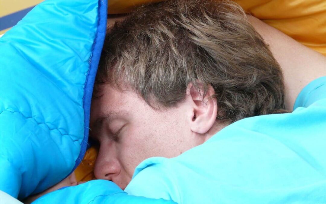 Person schläft in einem blauen Schlafsack