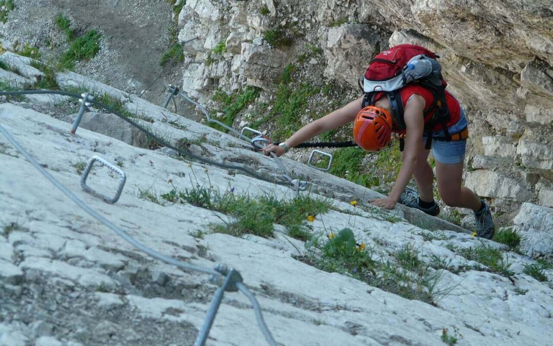Kletterer mit Sitzgurt, Helm und Rucksack am Klettersteig