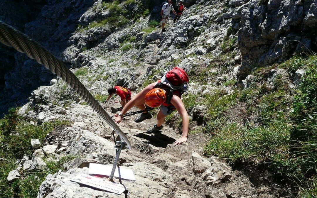 Klettersteigkurs mit mehreren Teilnehmern, Helm, Gurt und Klettersteigset am Stahlseil